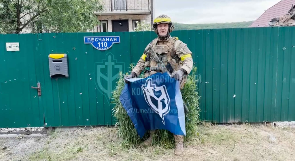 A fighter demonstrates a banner with the symbols of the RDK in Novaya Tavolzhanka.