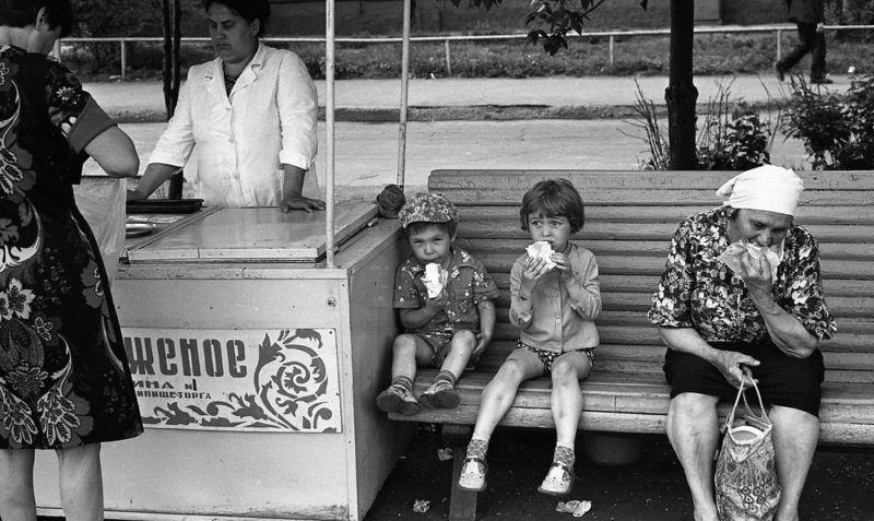 Children sit on a bench and eat ice cream